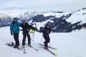 three men pose while skiing near Garmisch with mountains in the background